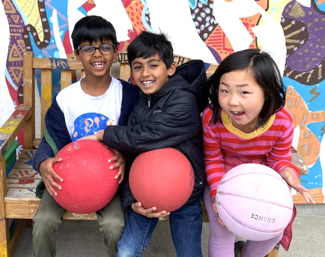 3 students outdoors, with balls